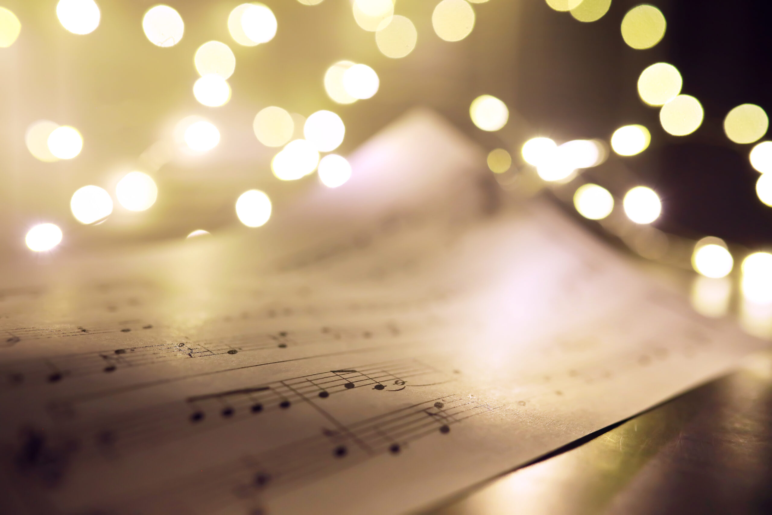 Old sheet with Christmas music notes as background, bokeh effect